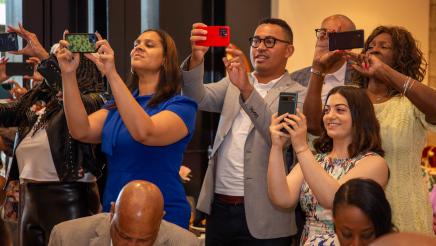 Multiple attendees taking photos with cell phones