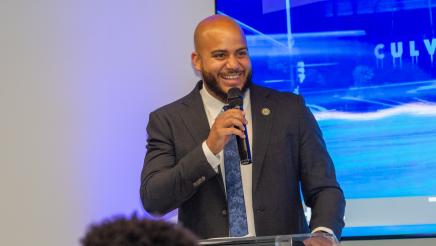 Asm. Bryan holding microphone, sharing a light moment with audience