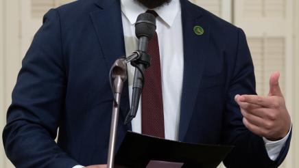 Asm. Bryan standing and speaking into microphone