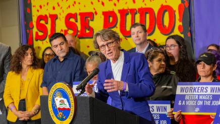 Mary Kay Henry, President of SEIU at podium, speaking, with bill supporters standing behind