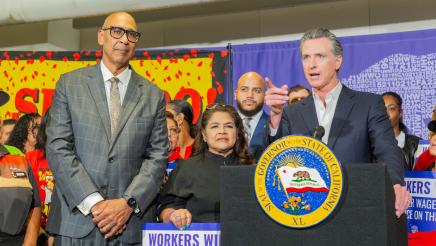 Asm. Bryan and Asm. Holden stand close as Gov. Newsom speaks
