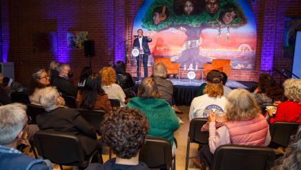 Host onstage, speaking to audience