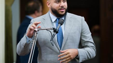 Asm. Bryan standing at microphone, speaking