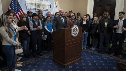 Asm. Bryan at podium, speaking, with multiple supporters in background