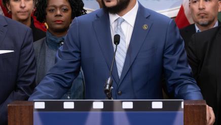 Asm. Bryan at podium, speaking, with supporters in background