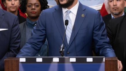 Asm. Bryan at podium, speaking, with supporters in background
