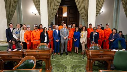 Group photo of Asm. Bryan and other members with incarcerated firefighters